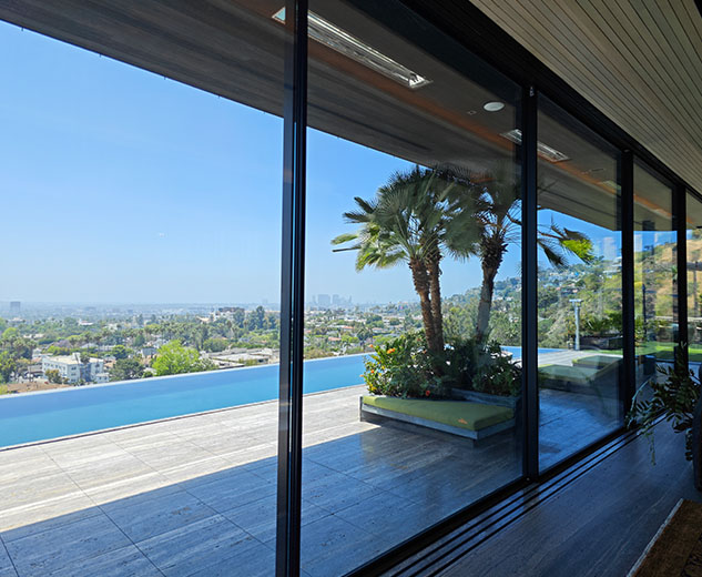 Ceramic window tint installed on large glass panels overlooking a pool in a luxury Hollywood mansion